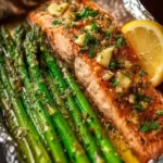 Baked salmon in foil served with asparagus and lemon garlic butter sauce