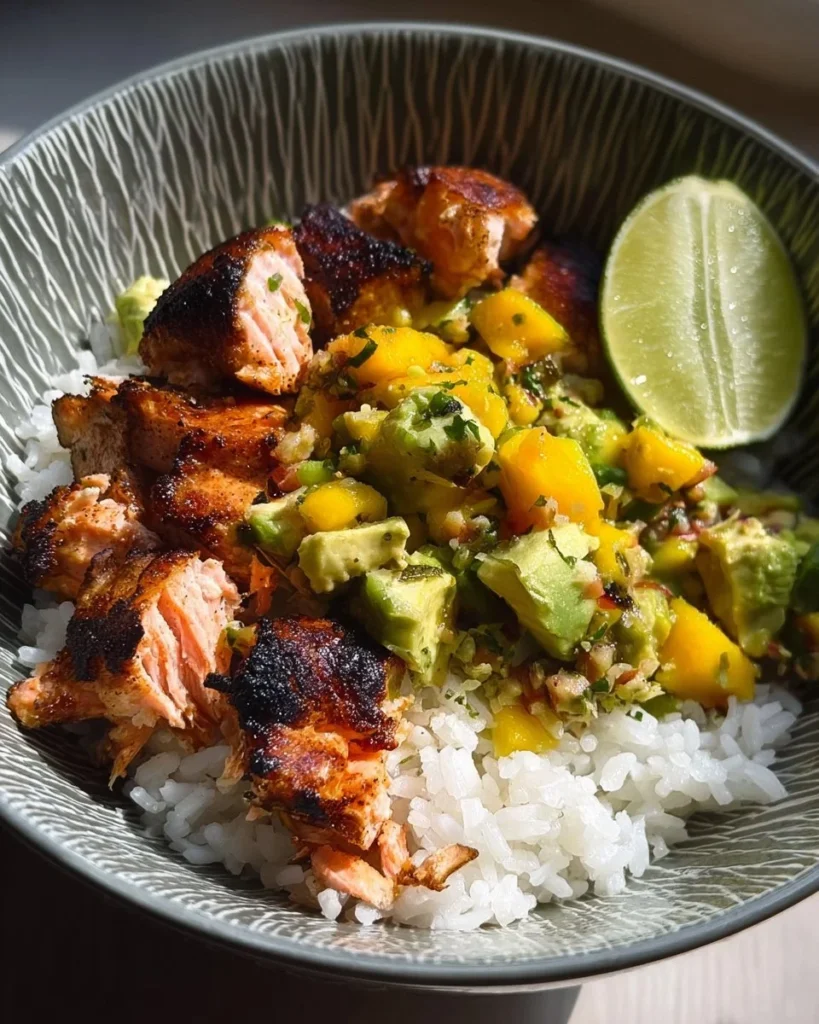 Blackened salmon fillet topped with mango avocado salsa on a plate.