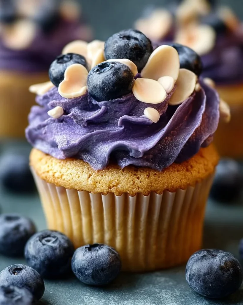 Blueberry pie cupcakes topped with fresh blueberries and creamy frosting.