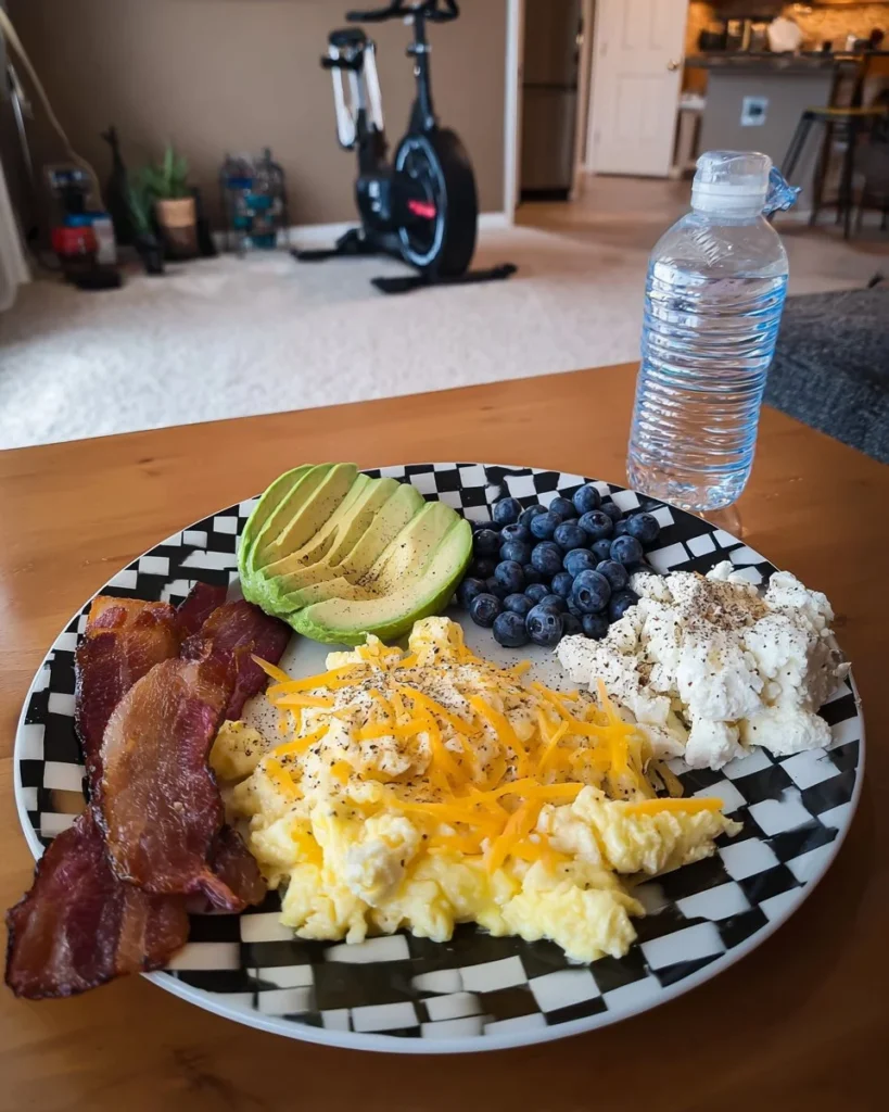 Cheesy scrambled eggs with crispy bacon and fresh avocado on a plate