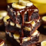Chocolate covered banana brownies on a plate, garnished with banana slices.