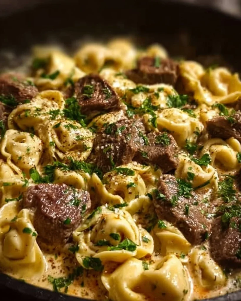 Creamy cheesesteak tortellini in provolone sauce served on a plate