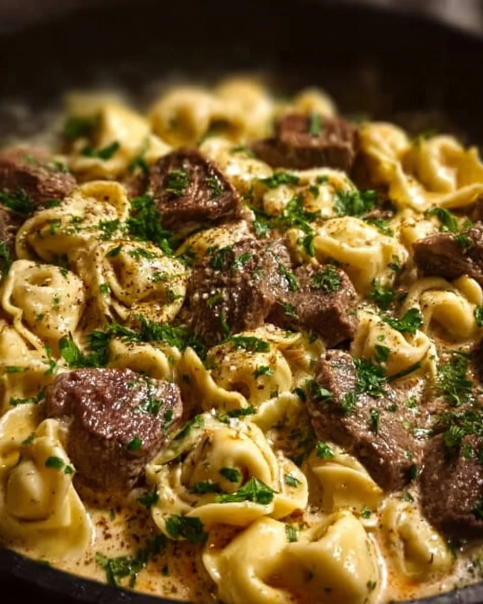 Creamy cheesesteak tortellini in provolone sauce served on a plate