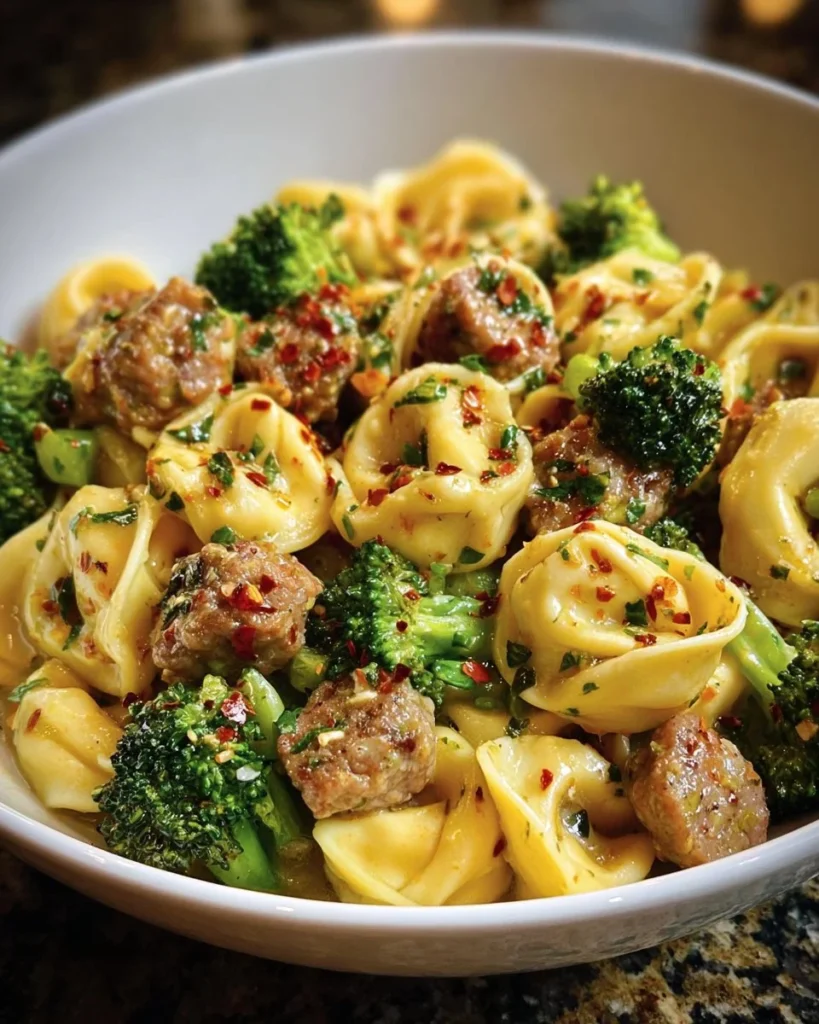 Creamy garlic parmesan tortellini with sausage and broccoli served in a bowl.