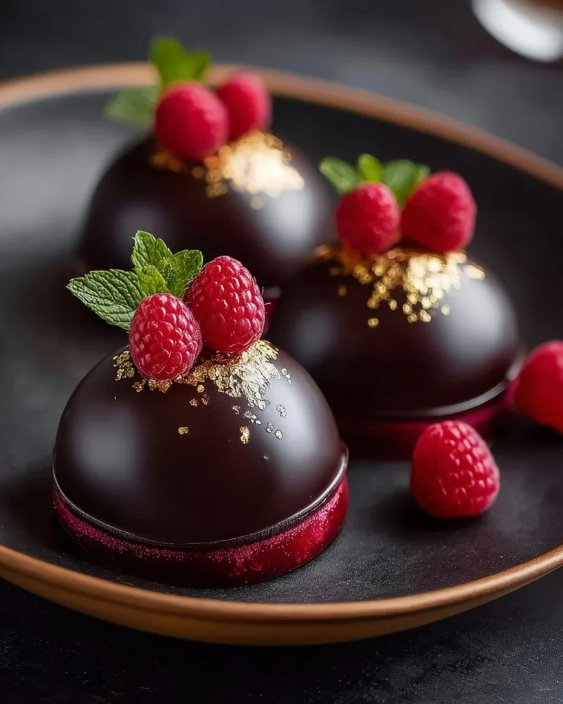 Dark chocolate raspberry mousse dome dessert with fresh raspberries and chocolate decor