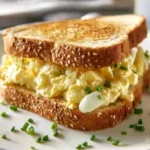 Egg salad sandwich with fresh ingredients on a wooden board
