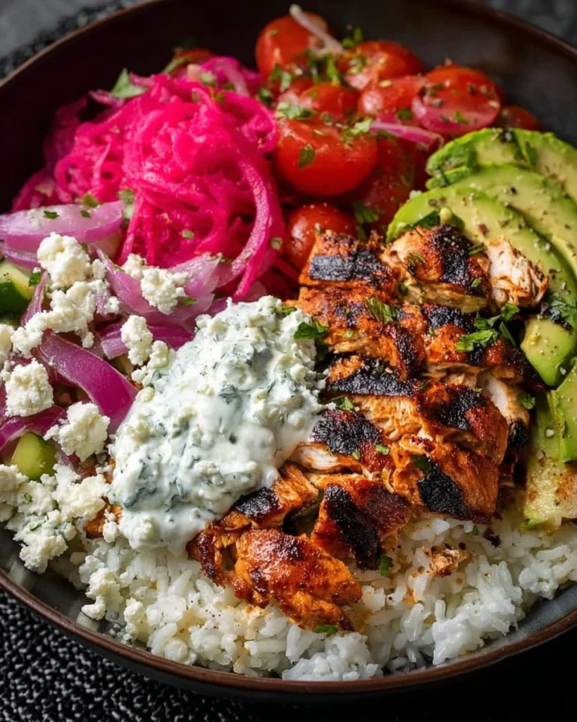 Greek-style chicken bowl featuring feta cheese, tzatziki sauce, and pickled onions