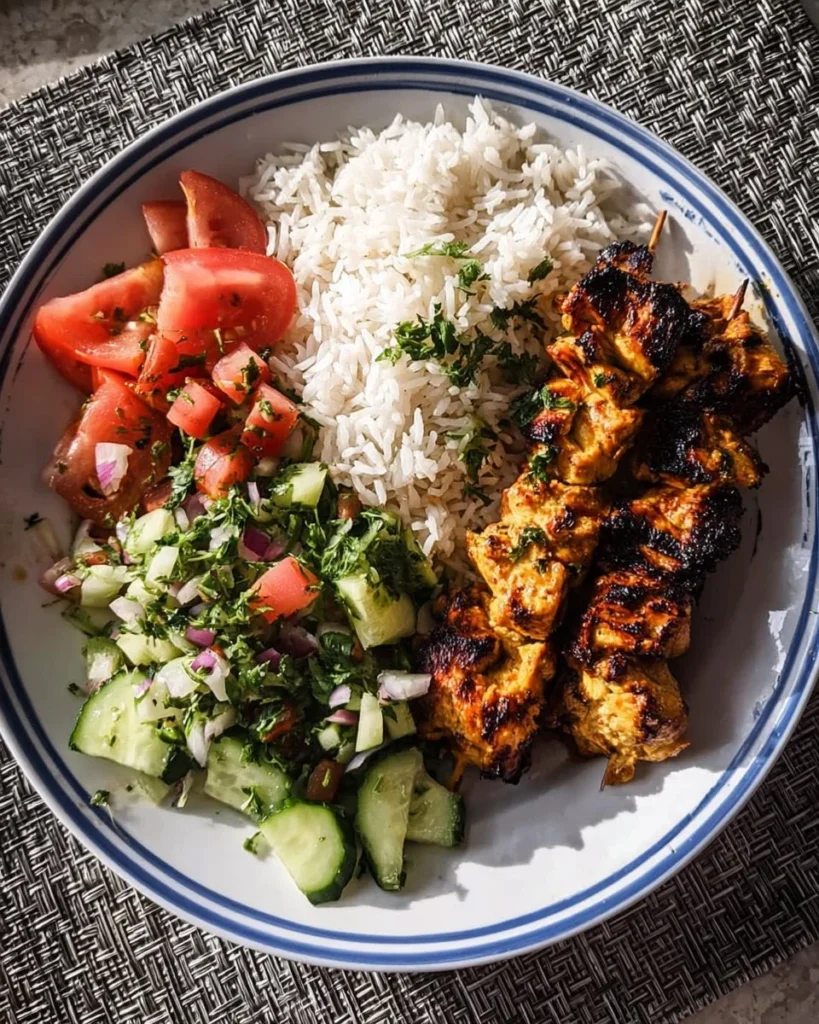 Grilled chicken skewers served with rice and a fresh salad on a plate.