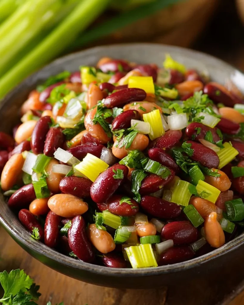 A colorful bowl of homemade three bean salad with fresh vegetables.