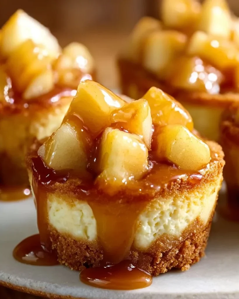 Mini caramel apple cheesecakes topped with caramel drizzle and apple slices.