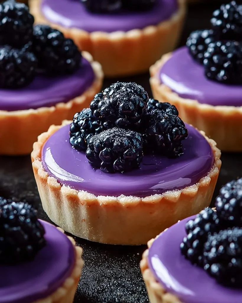 Mini tarts with creamy filling and a vibrant purple glaze