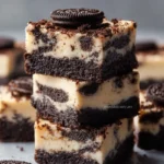 Oreo Cheesecake Bars topped with crushed Oreos on a white plate