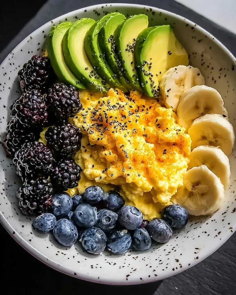 Power breakfast bowl featuring scrambled eggs, avocado, and mixed berries.