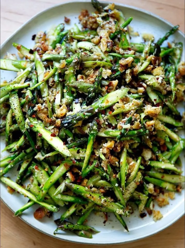 Raw asparagus salad topped with walnuts and Parmesan cheese
