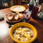 Scrambled eggs and cheese grits bowl served with toast on a breakfast table.
