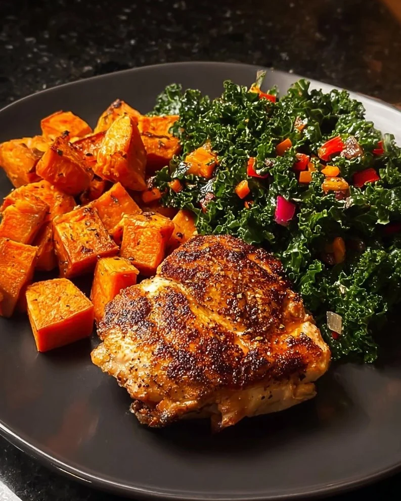 Plate of Spicy Garlic Chicken served with sweet potatoes and fresh greens.