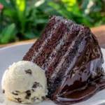 Triple chocolate cake topped with hot fudge sauce, a rich dessert delight.