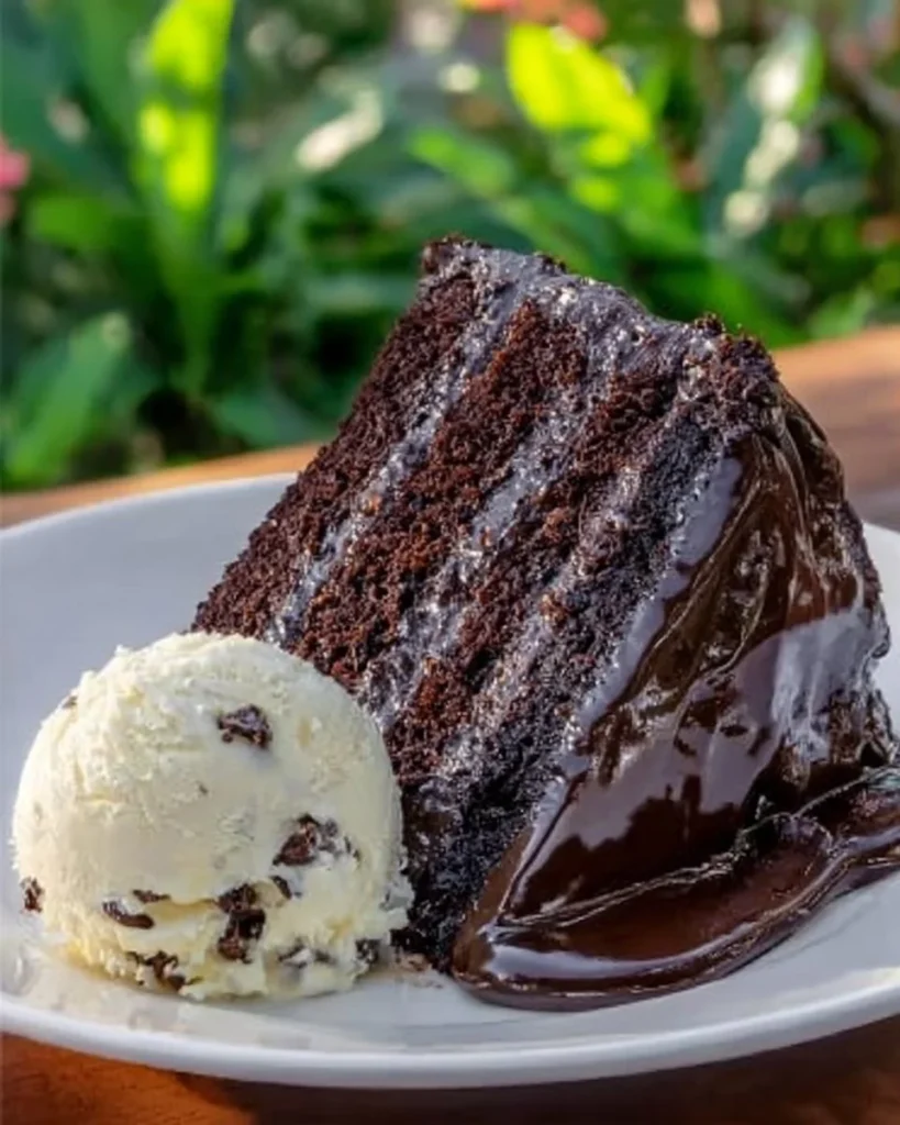 Triple chocolate cake topped with hot fudge sauce, a rich dessert delight.